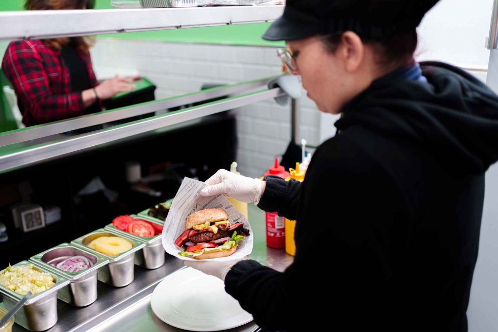Préparation d'un burger dans une cuisine équipée pour la restauration rapide.